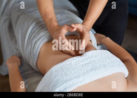 Junge schöne Frau, die im Spa eine Antikellulit-Bauchmassage genießt.professionelle Massagetherapeutin behandelt eine Patientin in der Wohnung.Entspannung Stockfoto