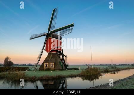 Atemberaubendes Landschaftsbild einer traditionellen holländerwindmühle bei Sonnenaufgang an einem kalten Morgen im Herbst Stockfoto