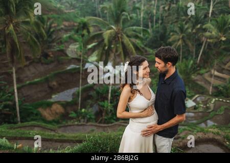 Junge latin schwangere Frau mit Mann mit atemberaubenden Blick von Ubud Reisterrassen. Schwangeren Paare glücklich zusammen. Stockfoto