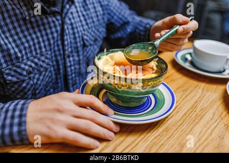 Man isst traditionelle asiatische Suppe aus gemusterter Holzplatte Stockfoto