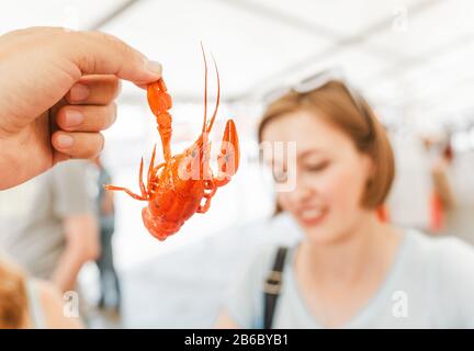 Junge Frau, die rot gekochte, köstliche Krebse oder Raupenflußlammer isst. Lokales Küche- und Meeresfrüchte-Konzept Stockfoto