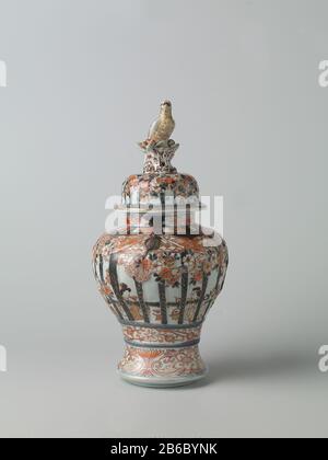 Balustervase mit Abdeckung für Menschen in einem inneren Heckgitter, prunusbäumen und Blumenrinnen Balustervormige Dekselpot van Porselein traf een spreidende voet, beschilderd in onderglazuur blauw en op het glazuur rood, zwart en goud. OP de Wand twee keer twee mensen zittend in een interieur achter gemodelleerd en beschilderd traliewerk. IT traliewerk is versierd met gemodelleerde en gedecoreerde prunusbomen en banden met bloemranken. Onder het traliewerk een Band met bloemranken. Rond de voet een Band met lotusranken. OP de hals drie Cartuches met lotusranken. Imari. Hersteller: Pottenbak Stockfoto