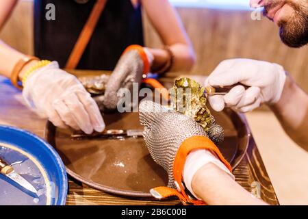 Frau öffnet im Restaurant eine Auster mit Messer Stockfoto