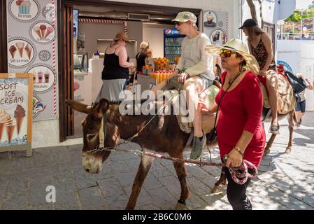 Rhodes, Griechenland - 14. Mai 2018: Frau auf dem Esel. Die Benutzung des Esels-Taxis zur Akropolis ist eine beliebte Touristenattraktion in Lindos Stockfoto