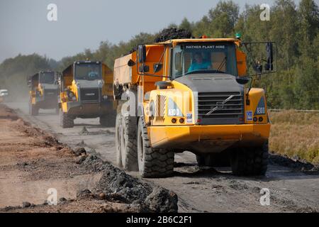 Komatsu & Volvo Müllkipper nehmen Backfill Material entlang einer Haustraße auf einem neuen Straßenbau in Doncaster, der als Great Yorkshire Way bekannt ist Stockfoto