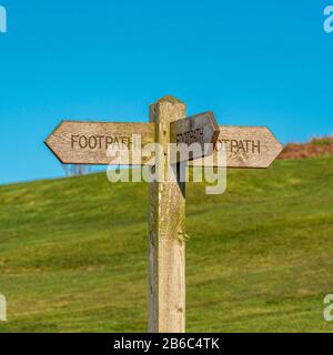 Holz-FuSspfad-Schild, das in verschiedene Richtungen zeigt Stockfoto