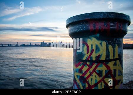 Ein Farbenfroher, Getaggter Pole am Grafitti Pier Mit der Skyline von Philadelphia im Hintergrund bei Sonnenuntergang Stockfoto