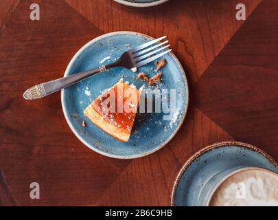 Die Überreste von Essen auf dem Tisch im Café, flacher Blick. Becher mit Kaffee und Gabel mit einem Teller mit Krümel aus einem Käsekuchen Stockfoto