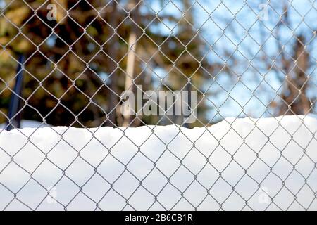 Der Gitterdraht mit Schnee und Eishimmel. Stockfoto