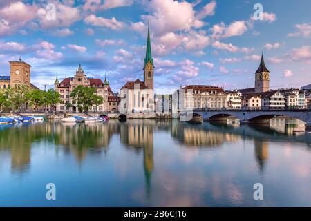 Berühmte Fraumunster- und Peterskirche mit Reflexionen in der Limmat bei Sonnenaufgang in Der Altstadt von Zürich, der größten Stadt der Schweiz Stockfoto