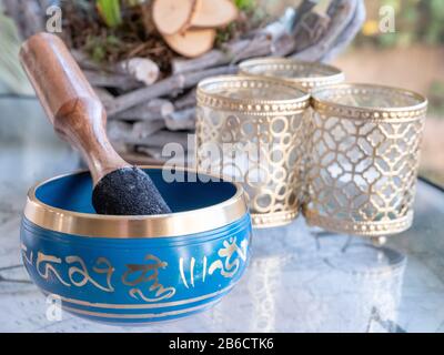 Haulerwijk - 07. märz 2020: Haulerwijk, Niederlande. Blaue und goldene indische Gesangsschale aus sieben Metallen mit einem Holzstreifer auf einem Glas Stockfoto