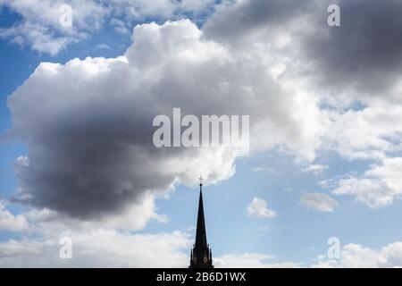 Eine Kirche und ein Kreuz oben sichtbar durch die Wolken Stockfoto