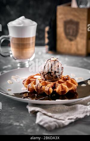 Wiener Waffeln mit Eis und Kaffee. Wunderschönes Dessertbild mit Lettenkaffee. Dessertkonzept, süßes Leben. Lebensmittelfoto, Kopierbereich, grau Stockfoto