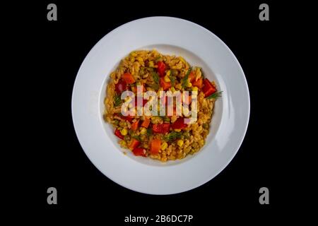 Gesunde Ernährung. Weißer Reis, Avocado, Kirschtomaten, grüne Erbsen und Haselnüsse weiße Platte isoliert auf schwarzem Hintergrund Stockfoto