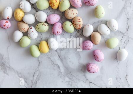 Frohe Ostern Konzept. Vorbereitung für den Urlaub. Ostern Eier in Pastellfarben Süßigkeiten Schokolade Bonbons auf trendige grauem Marmor Hintergrund. Einfache Minimalismus flach Ansicht von oben kopieren Raum Stockfoto