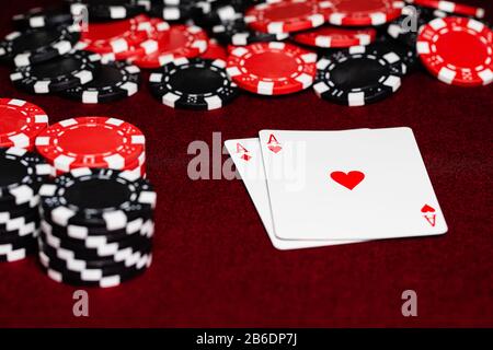 Ein Paar rote Asse, Diamanten und Herzen, auf einem roten Filztisch, umgeben von roten und schwarzen Ton-Pokerchips. Einige Zimmer sind für Kopien verfügbar unter Stockfoto