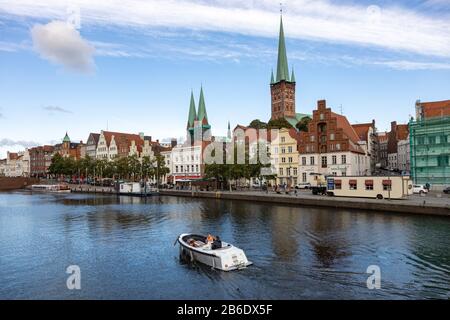 Lübeck, 10-06-2019 Blick über die Trave mit dem Motorboot in die historische Altstadt mit St. Petri (rechts) und Marienkirche Stockfoto