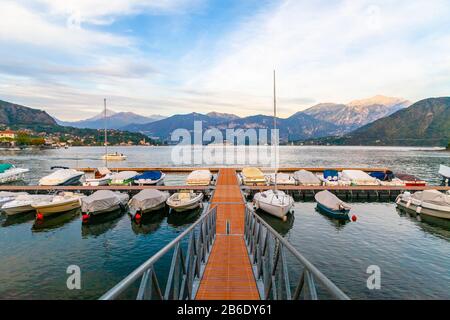 Ein Hafen am Comer See bei Sonnenuntergang, mit Anlegestelle und Booten Stockfoto