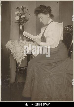 Buchleserin sitzt an einem Tisch mit einer Vase von Blumen Onderdeel van Familiealbum traf auf Onder Meer Foto's van Wijnhandel Kraaij & Co. Bordeaux-Amsterdam. Hersteller : fotograaf: Anoniem dating: CA. 1900 - ca. 1910 Physische Kenmerken: Mattes Dolchcollodiumzilverdruk platinagetoond Material: Fotopapier Techniek: Matt daglichtcollodiumzilverdruk Abmessungen: H 108 mm × b 78 mm Betreff: Anonyme historische Person dargestellt - BB - Womanlezencut Blumen; Nosegay, Blumenstrauß Stockfoto