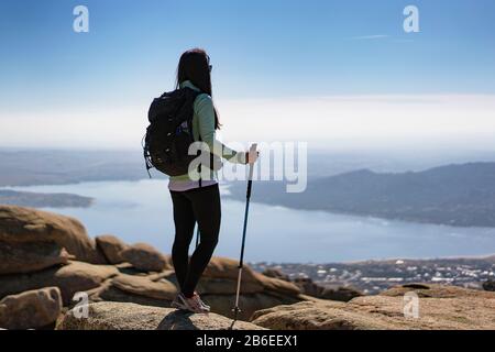 Panoramablick auf eine junge Frau in La Pedriza mit dem Santillana-Reservoir, Manzanares El Real, Madrid, Spanien. Stockfoto