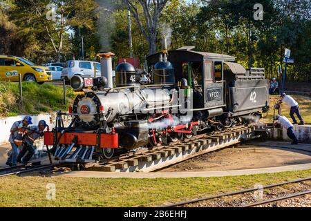 Arbeiter, die mit der Drehscheibe der Eisenbahn die Dampflok Richtung Sao Joao del Rey, Bahnhof Tiradentes, Stadt Tiradentes, Minas Gerais Brasilien drehen. Stockfoto