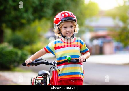 Kids on Bike im Park. Kinder in die Schule zu tragen sichere fahrradhelme. Little boy Radfahren auf sonnigen Sommertag. Aktiv gesund Outdoor Sport für y Stockfoto