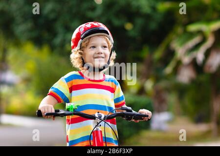 Kids on Bike im Park. Kinder in die Schule zu tragen sichere fahrradhelme. Little boy Radfahren auf sonnigen Sommertag. Aktiv gesund Outdoor Sport für y Stockfoto