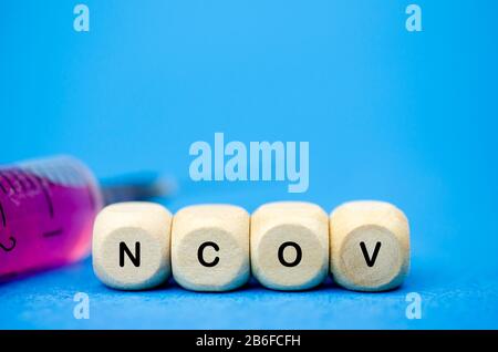 Die Aufschrift nCoV auf Holzwürfeln und SpritzeneHealth Concept, 2019 Coronavirus Stockfoto