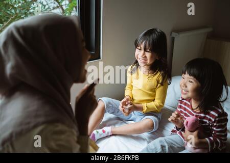 Die Mutter erzählt ihrer Tochter auf dem Bett, spielt zusammen Stockfoto