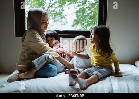 Die Mutter erzählt ihrer Tochter auf dem Bett, spielt zusammen Stockfoto