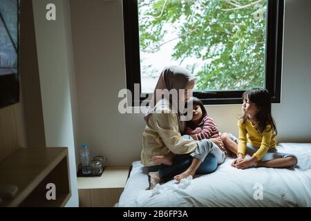 Die Mutter erzählt ihrer Tochter auf dem Bett, spielt zusammen Stockfoto