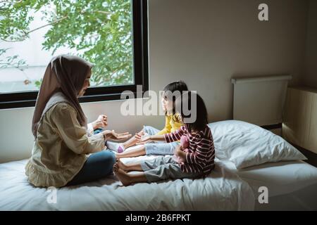 Die Mutter erzählt ihrer Tochter auf dem Bett, spielt zusammen Stockfoto