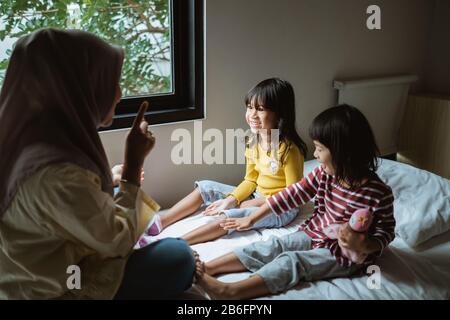 Die Mutter erzählt ihrer Tochter auf dem Bett, spielt zusammen Stockfoto