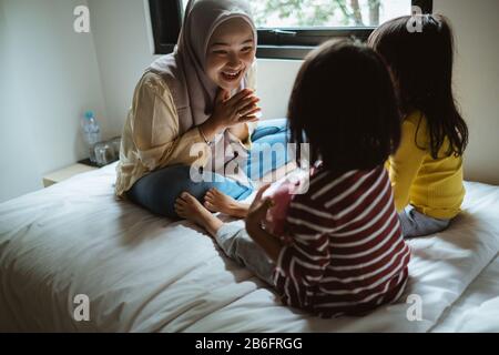 Die Mutter erzählt ihrer Tochter auf dem Bett, spielt zusammen Stockfoto