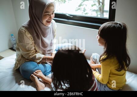 Die Mutter erzählt ihrer Tochter auf dem Bett, spielt zusammen Stockfoto