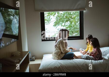 Die Mutter erzählt ihrer Tochter auf dem Bett, spielt zusammen Stockfoto