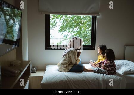 Die Mutter erzählt ihrer Tochter auf dem Bett, spielt zusammen Stockfoto