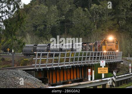 NGAHERE, NEUSEELAND, 2. SEPTEMBER 2019: Ein kleiner Kohlezug biegt die Ecke ab, um die Brücke am Ongionui Creek bei Ngahere an der Westküste zu überqueren Stockfoto