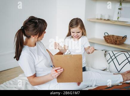 Mutter und Tochter spielen, Mädchen ist wütend, sie lebt negative Emotionen. Kinderpsychologische Bildungsspiele Stockfoto