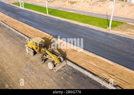 Straßengrader auf Straßenbaustelle. Maschinen arbeiten am Bau neuer Straße. Luftbild Stockfoto