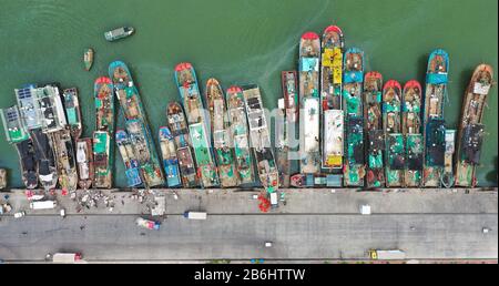 Peking, China. März 2020. Das Luftbild vom 10. März 2020 zeigt Menschen, die Fische aus den Fischerbooten am zentralen Fischereihafen Yazhou in Sanya, Südchinas Provinz Hainan, entladen. Credit: Guo Cheng/Xinhua/Alamy Live News Stockfoto