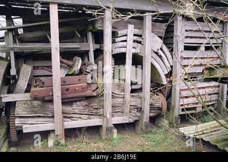 Alte rustikale Holzlagerhütte mit rostigen Maschinenteilen und unter Deckeln gestapelten Industriegetrieben mit offenen Wänden in Nahaufnahme Stockfoto