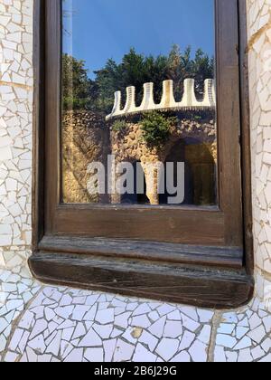 Zerbrochene Glasmosaikfliesen als Keramikkunst an der Gebäudewand und Spiegelung des Glasfensters im Park Guell, Barcelona, Spanien Stockfoto