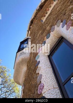 Zerbrochene Glasmosaikfliesen als Keramikkunst an der Gebäudewand mit dem blauen klaren Himmel im Park Guell, Barcelona, Spanien Stockfoto