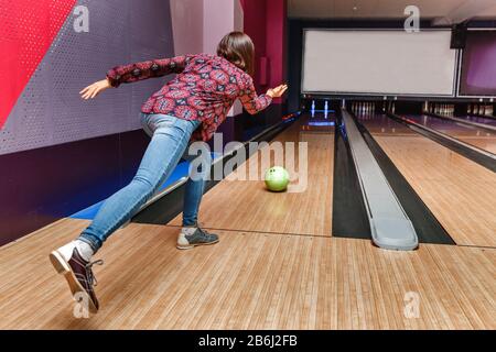 Eine Frau in einem Bowlingclub wirft einen Ball auf den Weg, in der Hoffnung, einen Streik auszuklopfen Stockfoto