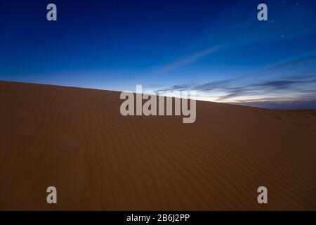 Nacht dramatischer Himmel über sandiger Wüste vor Sonnenaufgang Stockfoto