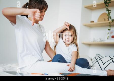 Mutter und Tochter spielen mit negativen Emotionen. Familie im hellen Interieur Stockfoto