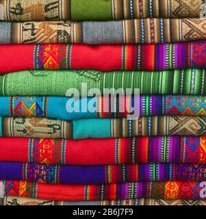 Ein Haufen farbenfroher Andentextilien, fotografiert auf dem lokalen Kunsthandwerksmarkt von Cusco, Peru Stockfoto