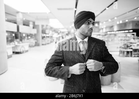 Junger gutaussehender indischer Sikh-Geschäftsmann, der Turban in der Stadt trägt Stockfoto