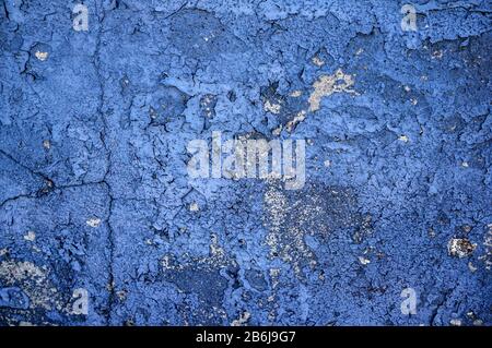Blau lackierte Zementwand mit tiefen Rissen aus Alter und Niederschlag. Formular für den Designer. Blaue Betonwand. Stockfoto